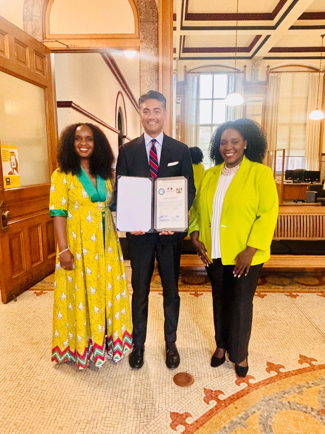 Two women and a man holding a signed city proclamation in a historic building